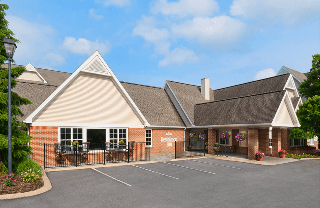 Hotel exterior with parking lot and trees.