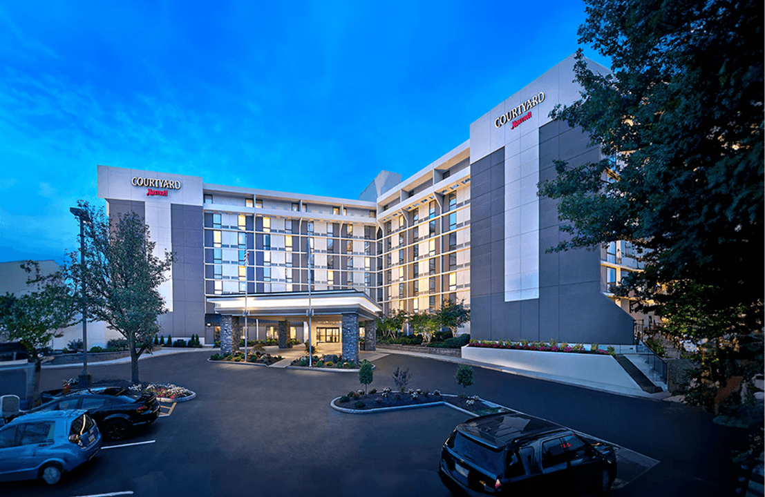 Modern hotel exterior with cars in parking lot.
