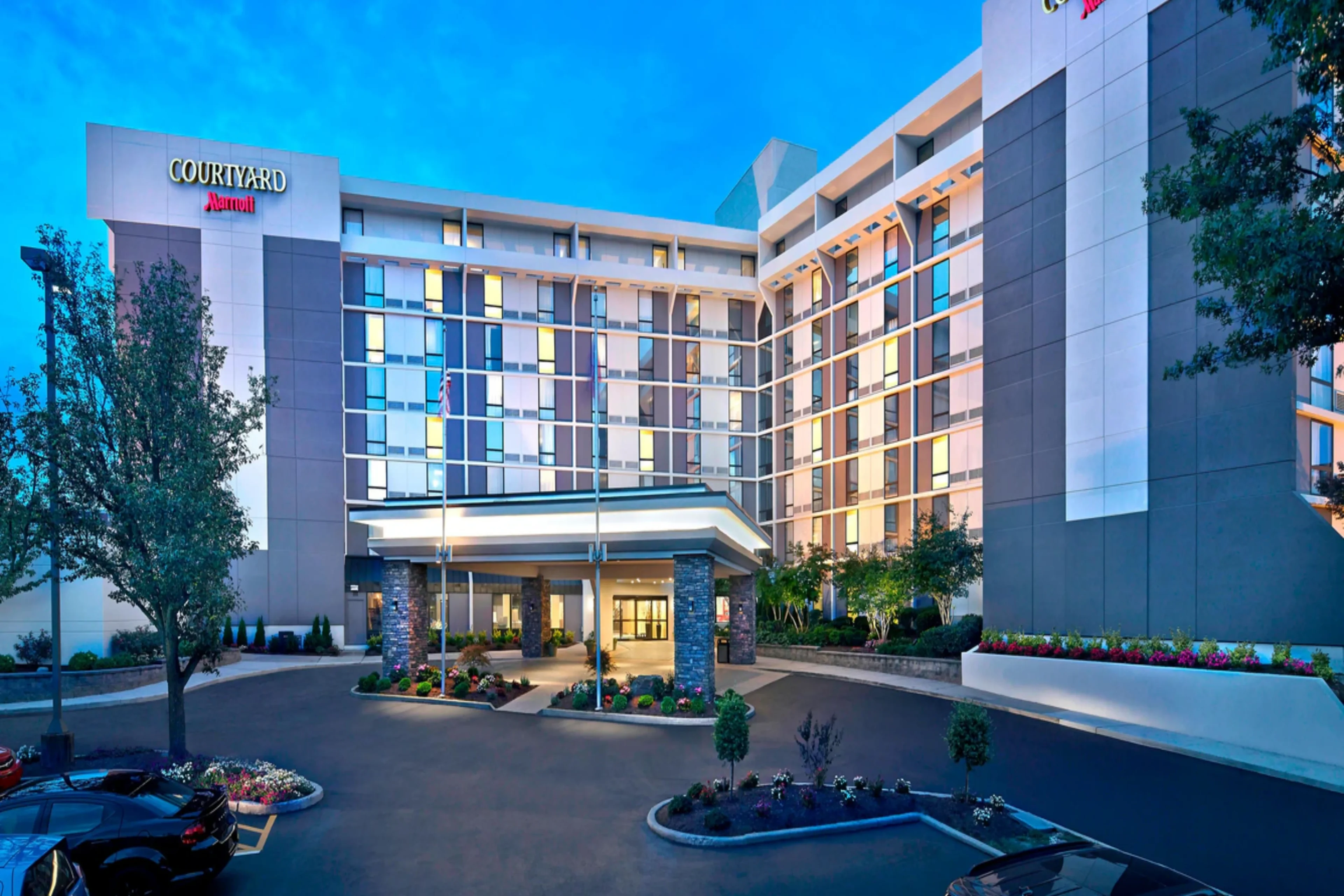 Modern hotel exterior with illuminated windows at dusk.