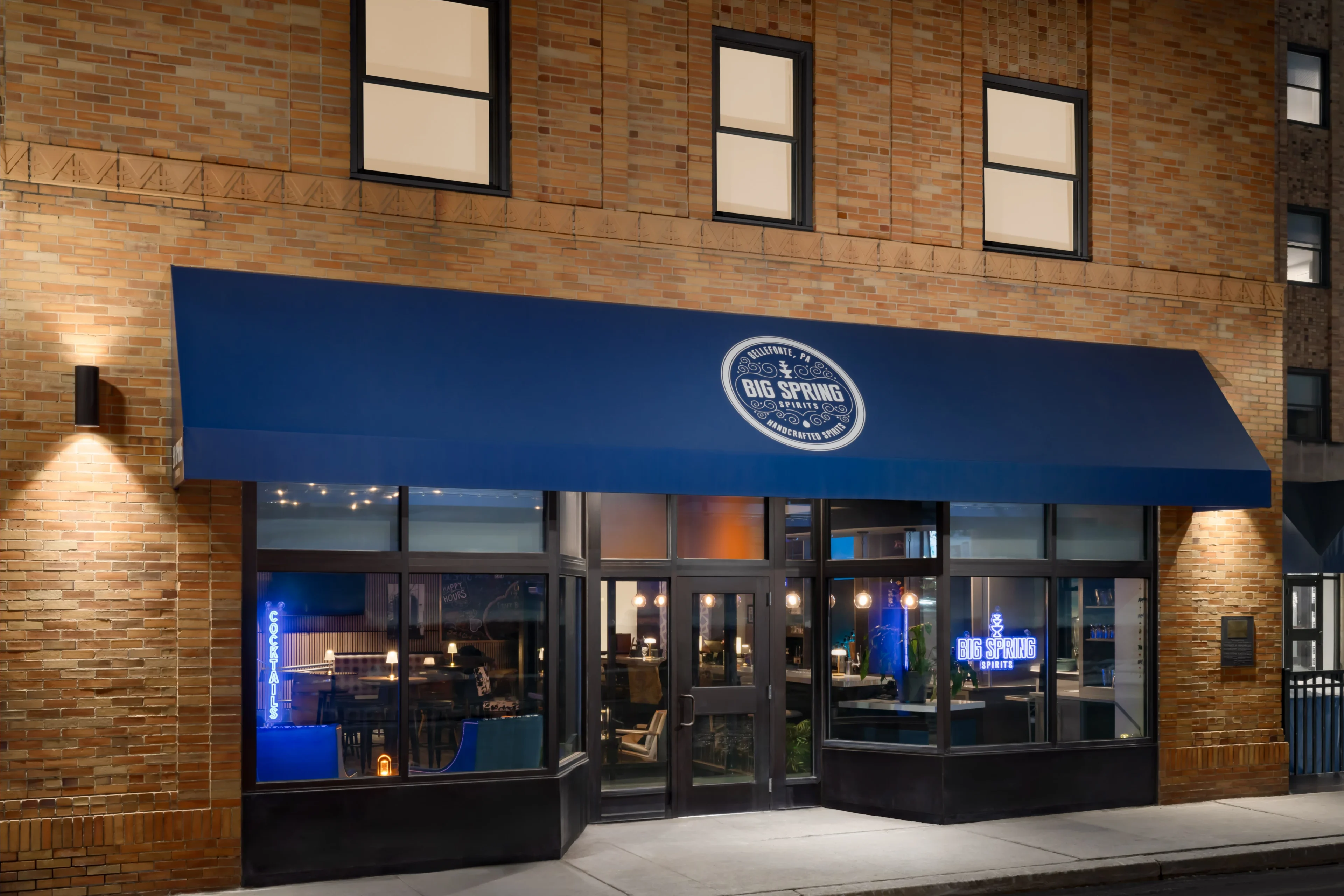 Restaurant exterior with blue awning at night.