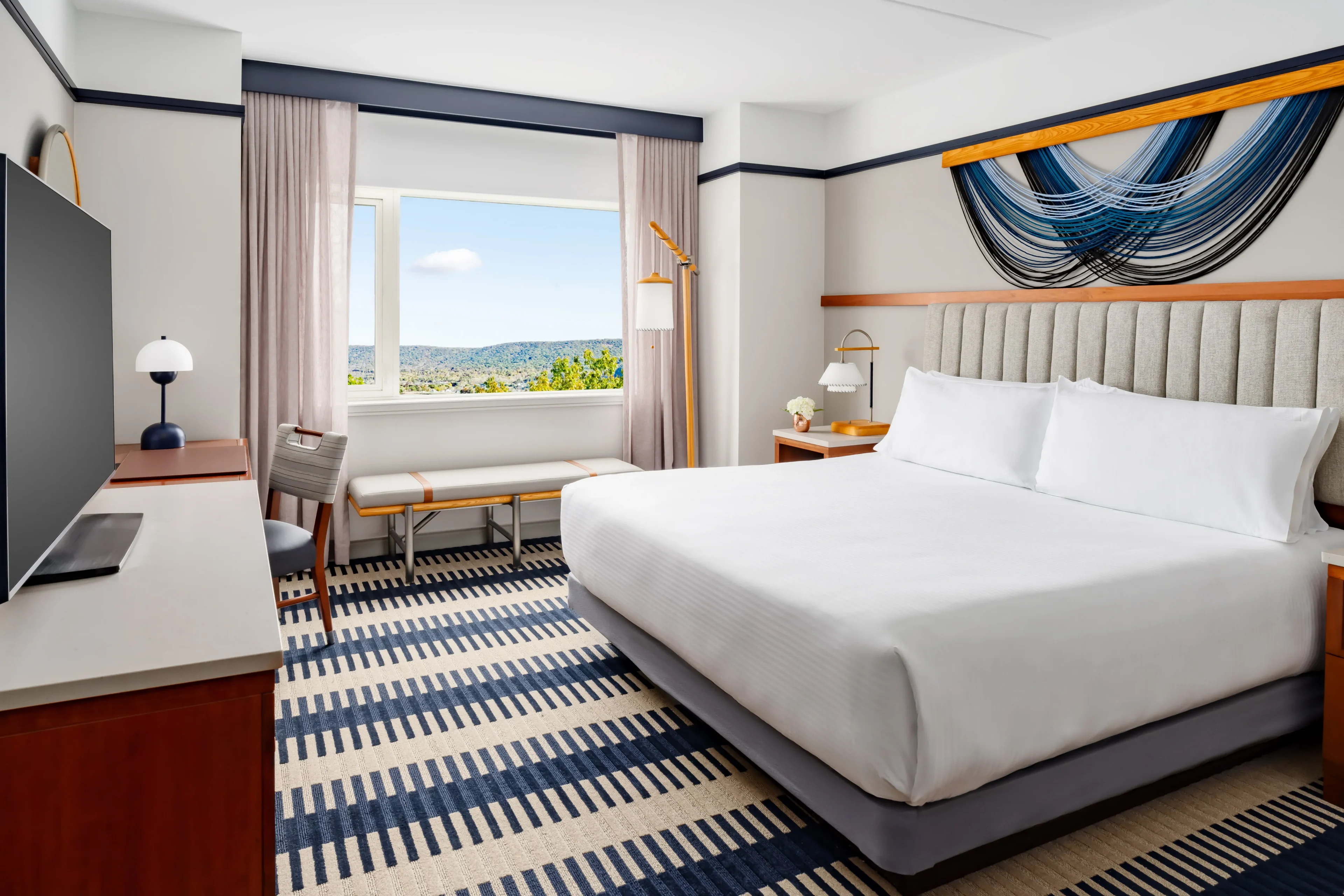 Modern hotel room with large bed, window view.