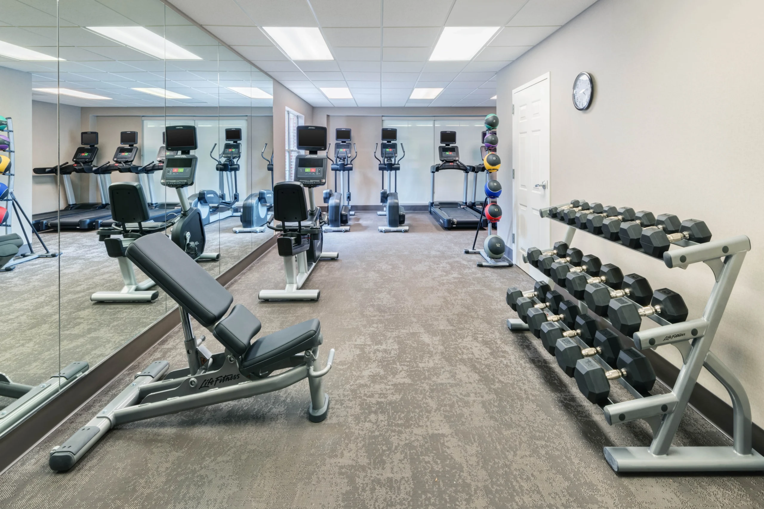 Small gym with exercise equipment and mirrors.