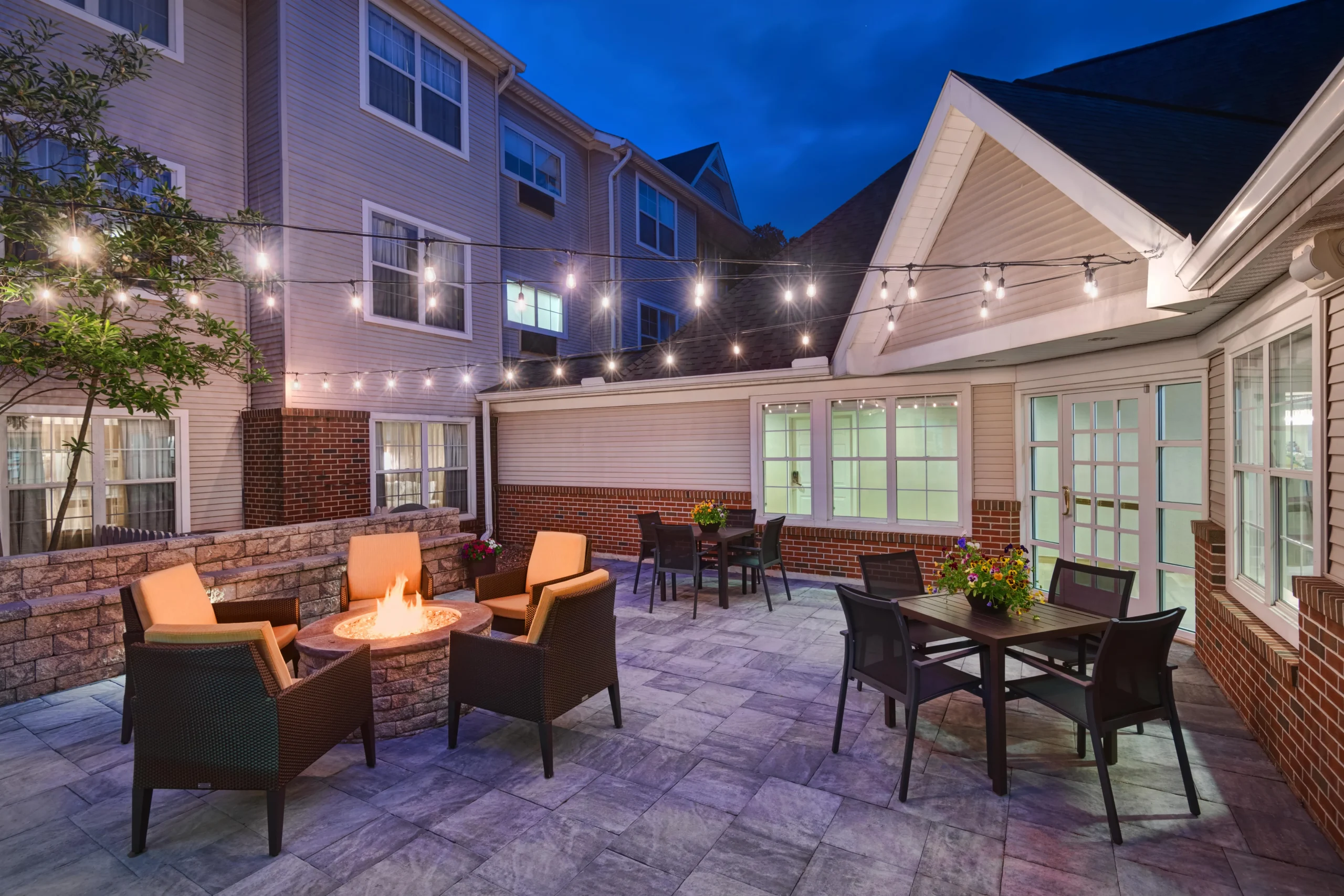 Cozy patio with fire pit and lights.