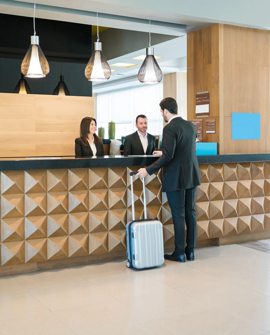 Man checking in at hotel reception desk.