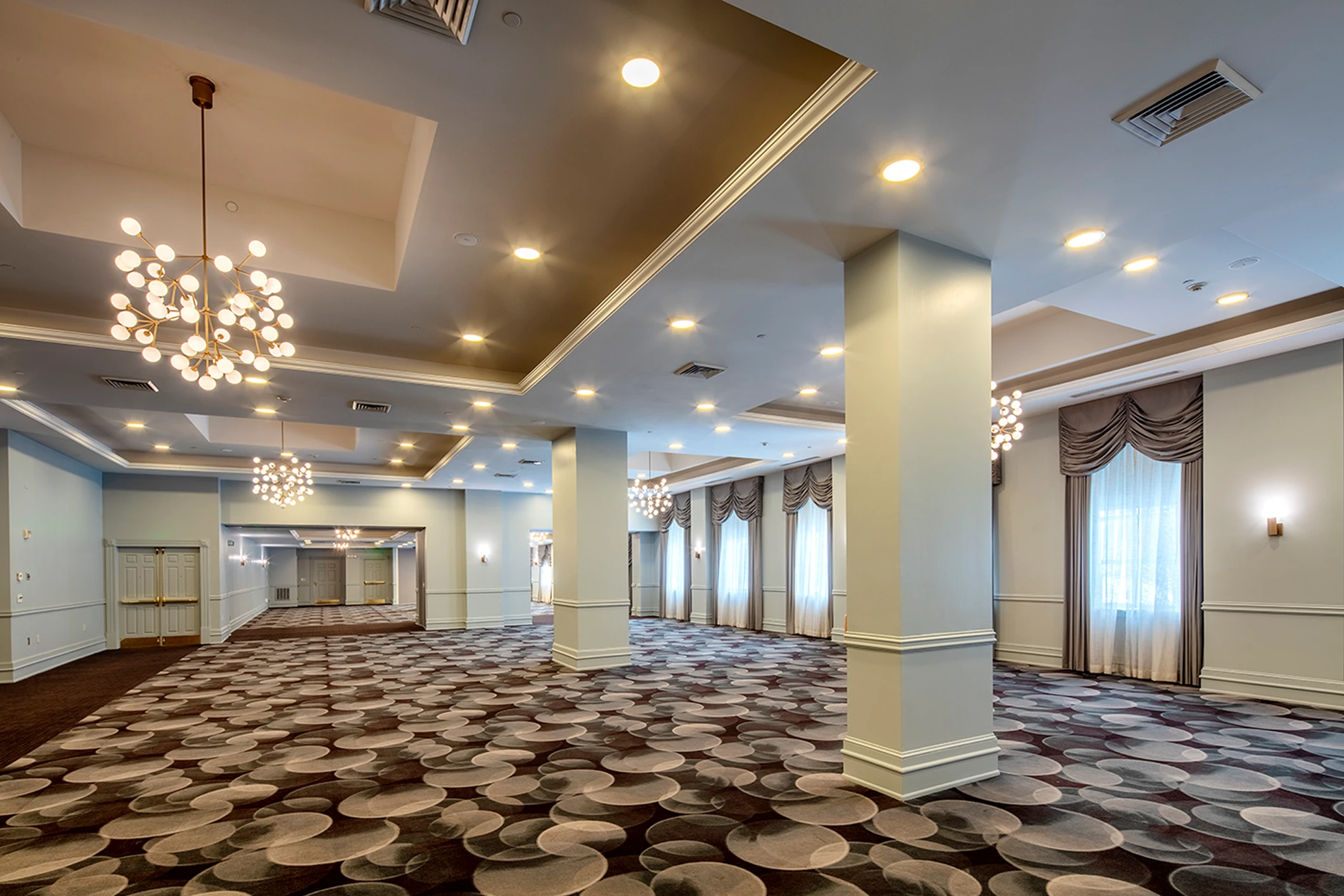 Elegant, spacious ballroom with modern lighting fixtures.