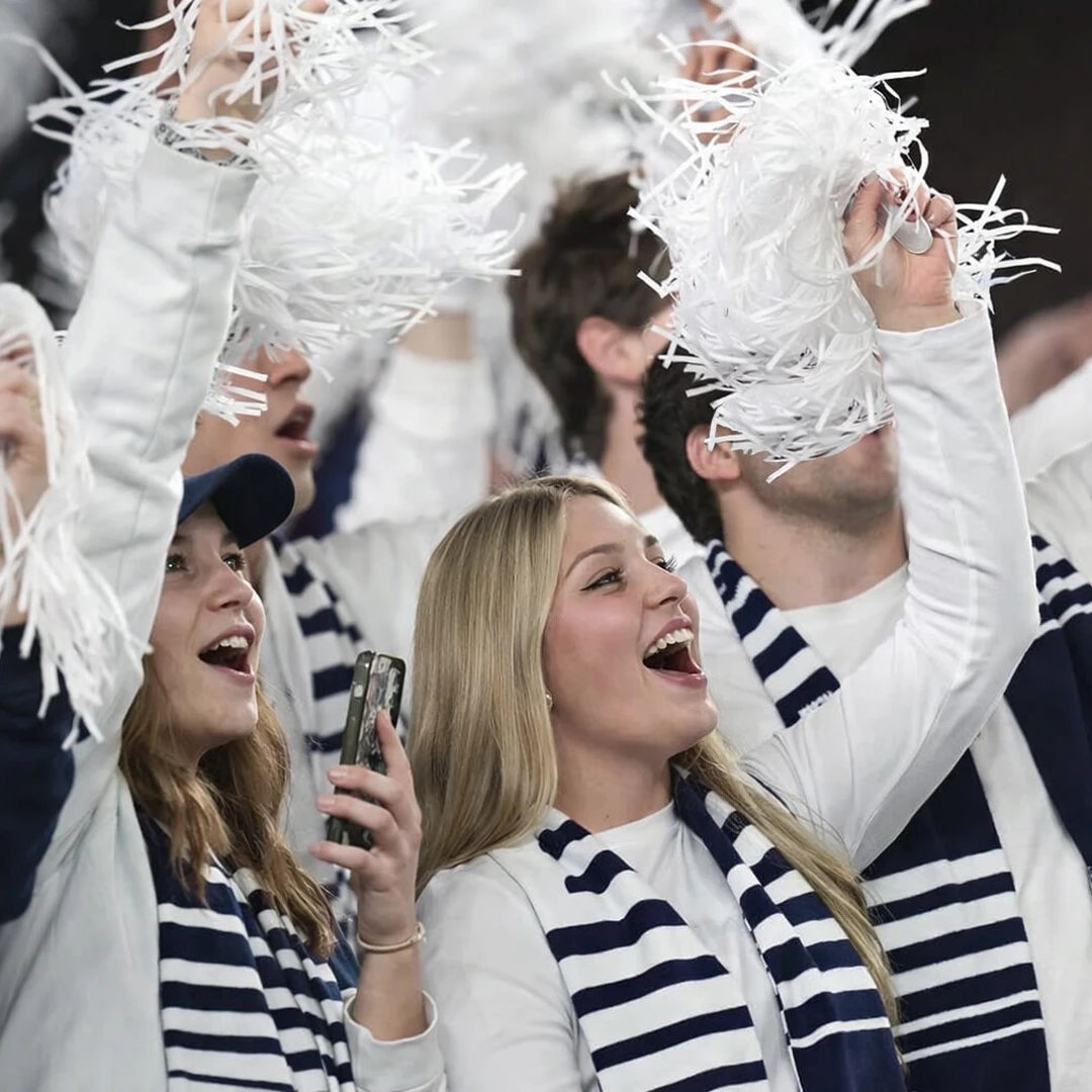 Cheering fans with pom-poms and scarves.
